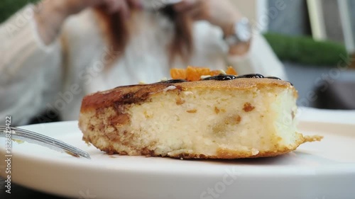 A girl in a cafe is eating dessert and drinking cappuccino, chatting on social media. A woman in casual clothes is sitting in the cafe, holding a smartphone in her hand and looking at it. 