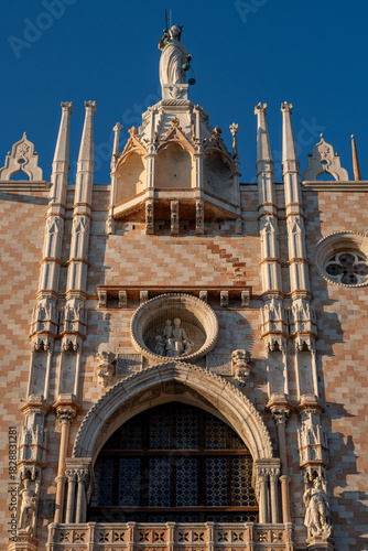 Golden evening light on ornate Gothic façade of Doge’s Palace in Venice with marble statues, arches and intricate stone tracery.