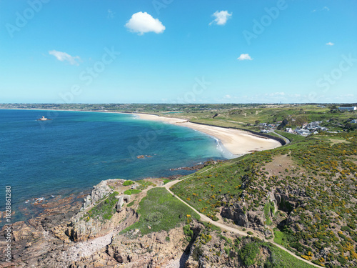 Aerial view of St Ouen’s Bay. Clear turquoise water, a sandy beach and rugged coastal cliffs. Jersey Island, British Channel Islands