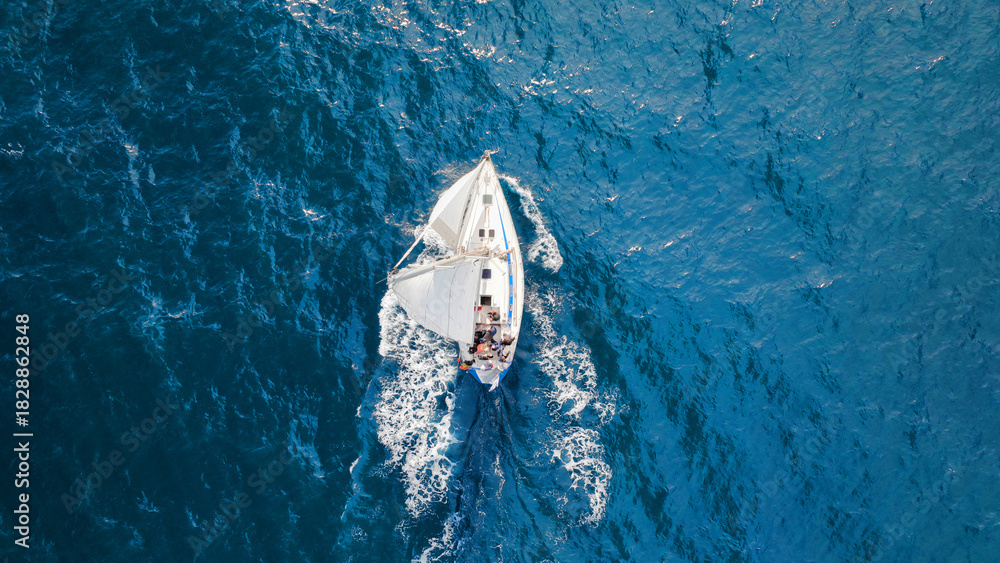 Fototapeta premium Aerial drone photo of beautiful sail boat with white sails cruising deep blue waves in Aegean sea