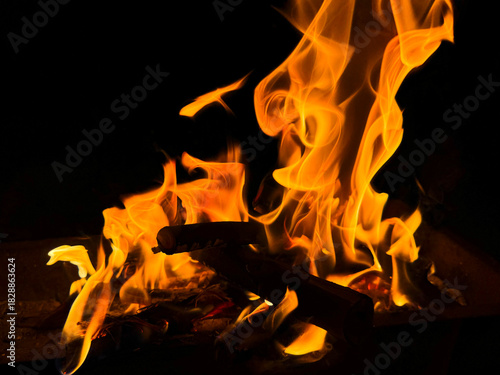 Bright campfire burning at night with vivid orange flames and glowing wood