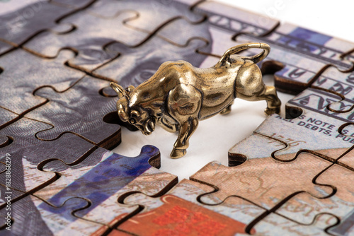 Fotografie A golden bull (taurus) and a US $100 bill made of puzzle pieces