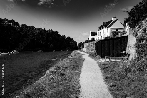 A black and white photo of a river with a house in the background
