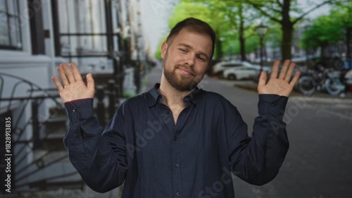 Man shrugging with palms up and tilted head on a cobblestone city street, wearing navy button shirt and beard; nonchalant acceptance.