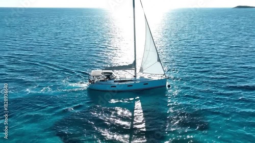 Sailboat gliding across clear turquoise ocean waters under bright sunlight creating a sense of luxury and adventure on the high seas