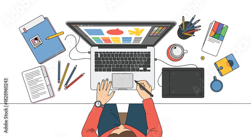 Top down view of a graphic designer or illustrator working on a laptop with a graphics tablet at a modern clean desk.