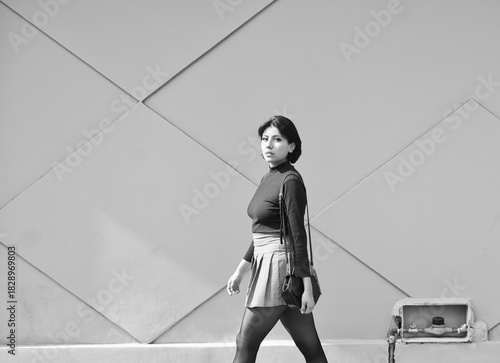 Woman walking urban street with geometric wall pattern