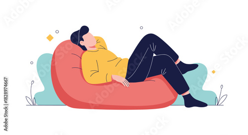 Young man in a yellow sweater comfortably relaxing and daydreaming while lying back in a large red bean bag chair.