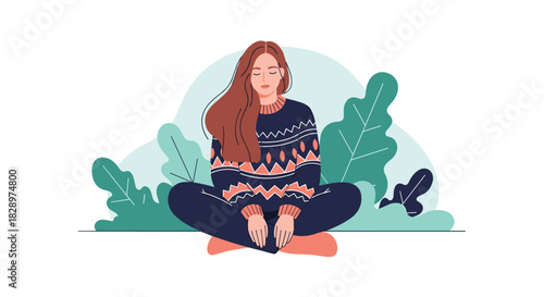 Calm young woman in a cozy sweater meditating with her eyes closed while sitting cross-legged against a leafy background.