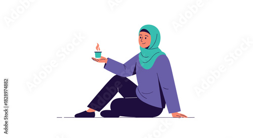 Young Muslim woman in a green hijab smiling while sitting on the floor and holding a warm cup of tea or coffee.