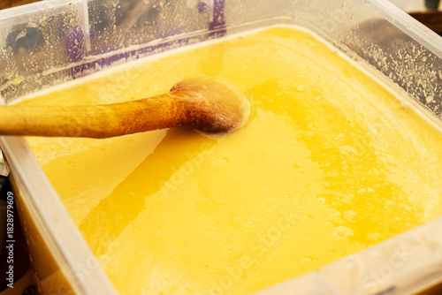 Texture of honeycombs close up. Yellow wax honeycombs with honey in plastic containers. Sale of homemade honey at the fair.