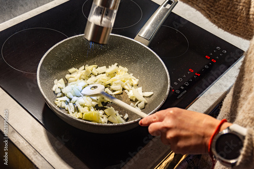 Fotografi Person adding seasoning to onions in frying pan