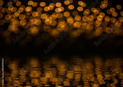 Beautiful blurred gold yellow bokeh from ornamental lights flickering with reflection on water ripple effect. Background for celebrate party, merry Xmas, happy new year concept.