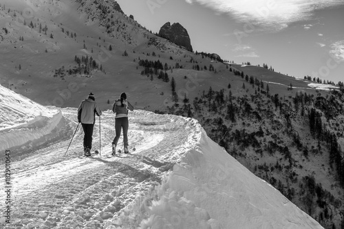 A couple skinning up a pisted track in Le Tour skiresort in the French Alps. In black and white.