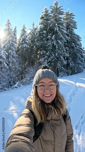 Happy woman taking selfie video in snowy winter forest