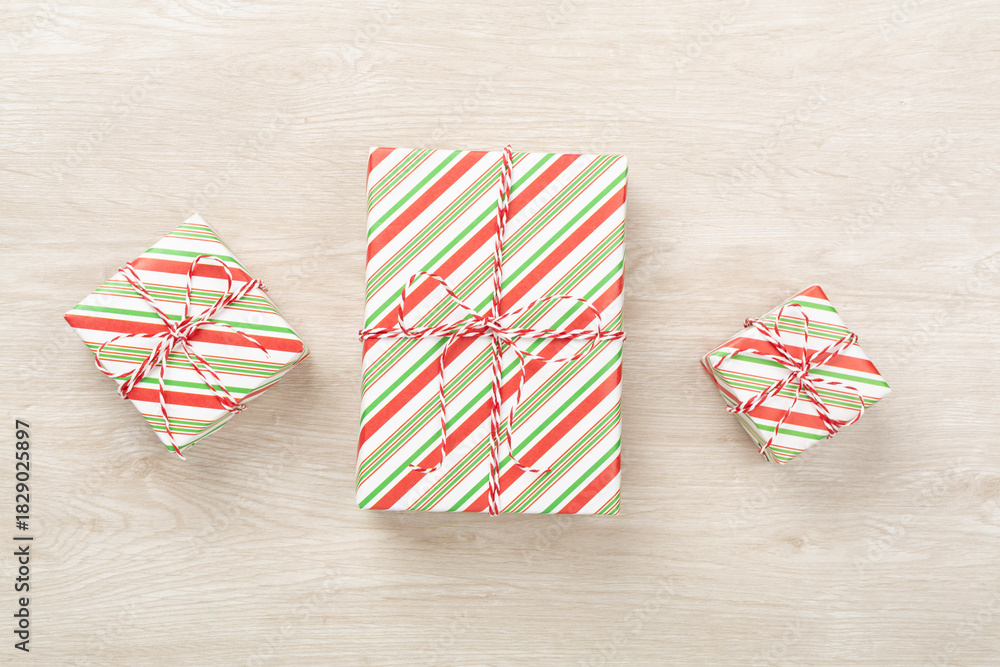 Fototapeta premium Striped Christmas gift boxes on wooden background, top view