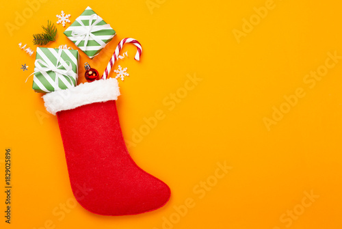 Christmas sock with gifts and decoration on color background, top view