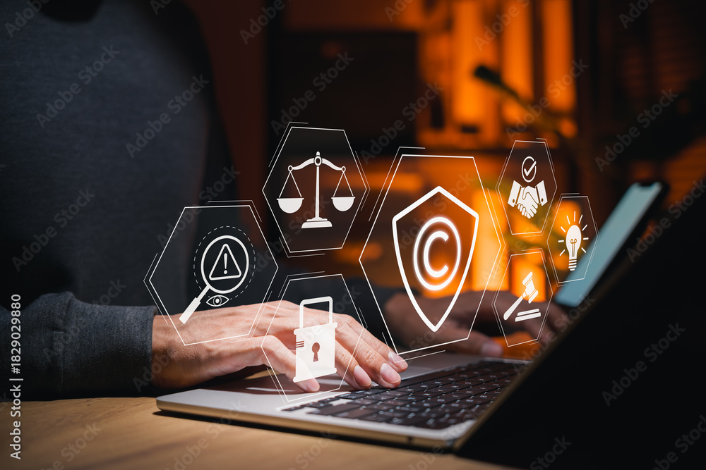 Obraz premium Businessman using laptop with copyright protection and intellectual property icons, represent digital rights management, online security, legal ownership, content regulation, copyright law enforcement
