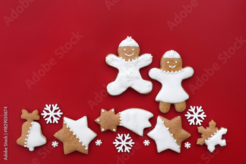Decorated gingerbread cookies of various shapes on a red background, copy space for text. Christmas baking