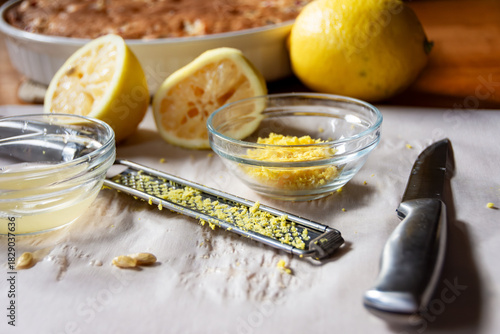Preparing fresh lemon glaze: zest, juice, lemon rinds, and microplane near the baked cranberry cake. Natural, homemade food preparation.