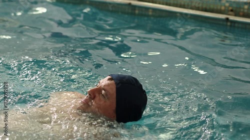 overcoming challenges, rehabilitation pool, exercise environment. Man swimming with one arm, emphasizing overcoming physical challenges.