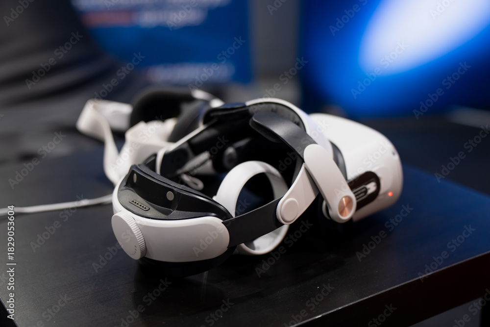 Fototapeta premium Virtual reality headset with comfort strap system and side controls placed on a dark surface during a technology event or immersive simulation setup