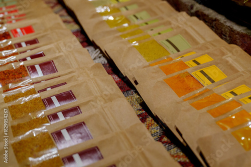Colorful packets of ground spices arranged in rows on market stall
