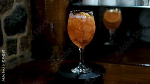 glass of classic red spritz cocktail with ice and orange slices on green garden background. High quality 4k footage