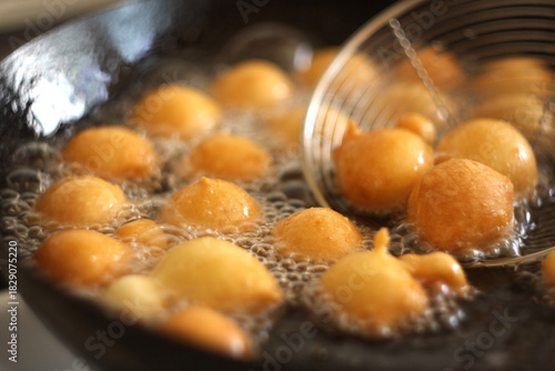 Fritule - Croatian mini doughnuts. Oil frying process. Selective focus