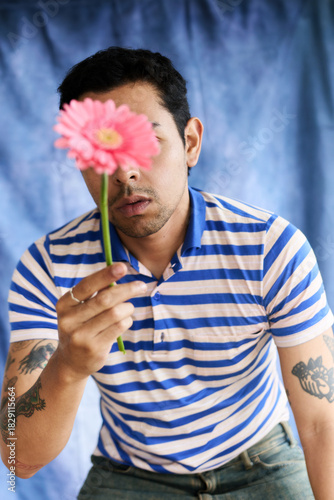 Chico joven latino sosteniendo flor sobre su rostro en sesión fotográfica 