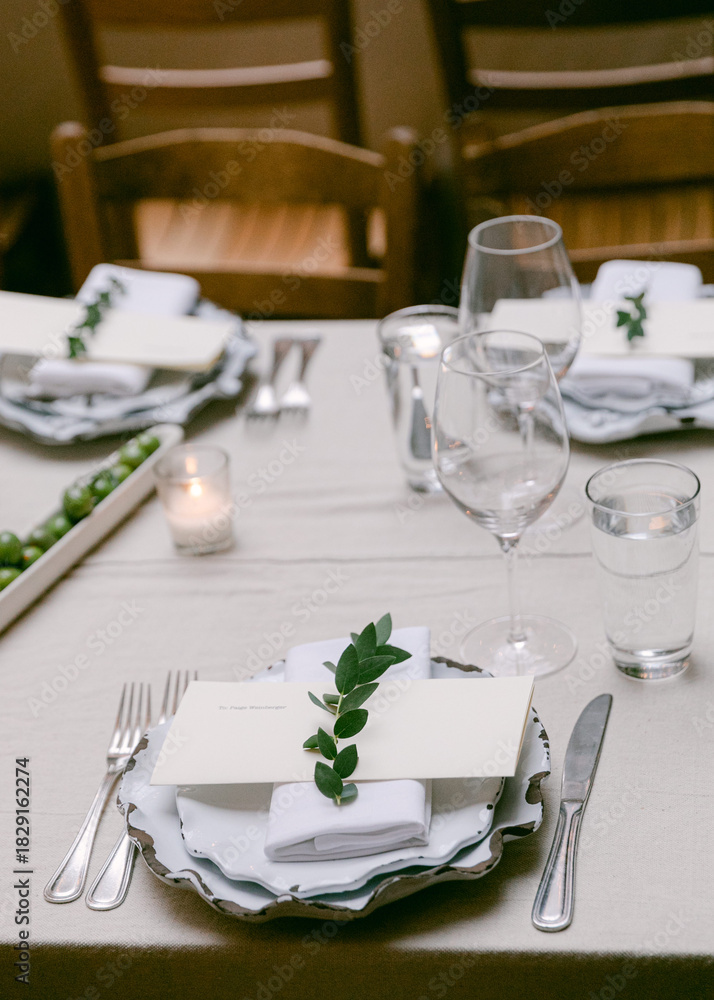 Fototapeta premium Elegant dinner setting with fresh greenery and simple tableware at a cozy restaurant