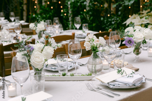Elegant outdoor dining setup with flowers and candles in a cozy garden at dusk