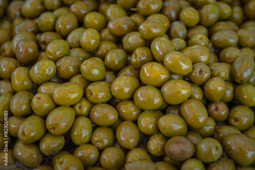Glossy green olives tightly packed in brine, smooth and oval-shaped