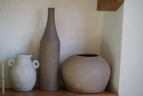Elegant minimalist ceramic vases and pots displayed on wooden shelf in contemporary interior design setting with soft natural light