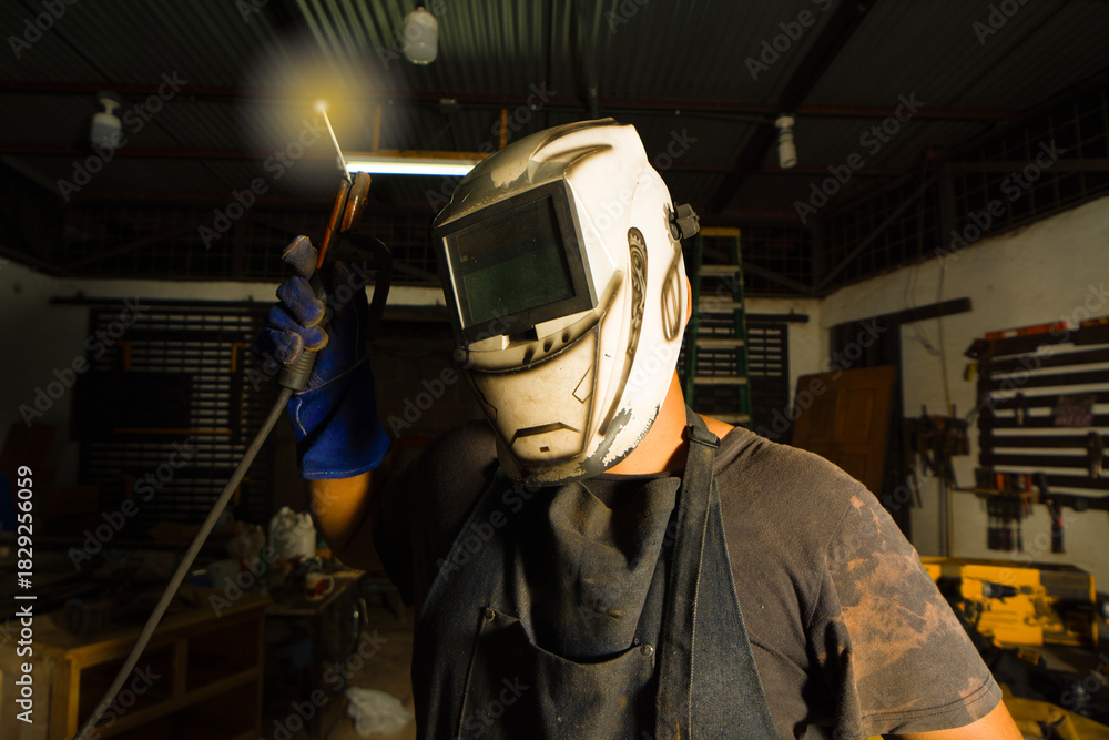 Fototapeta premium Welder threatening cameraman with welding torch. Welding professional showing a welding torch in the workshop