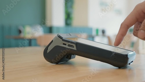 Close-up hand of a customer tapping credit card with a payment terminal or credit card machine at a cashier in a restaurant. cashless payment, card reader, electronic funds transfer