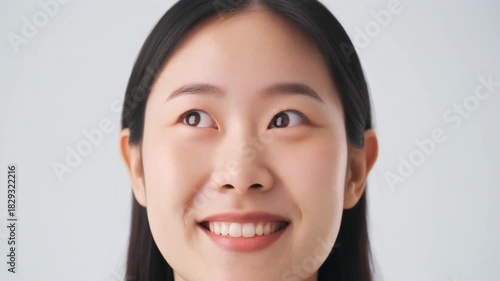 Close-up of a young Asian woman looking up against a white isolated background.