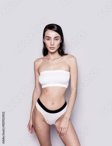 Gorgeous young woman with perfect body shape wearing lingerie underwear top and panties looking fresh happy and healthy posing on gray background