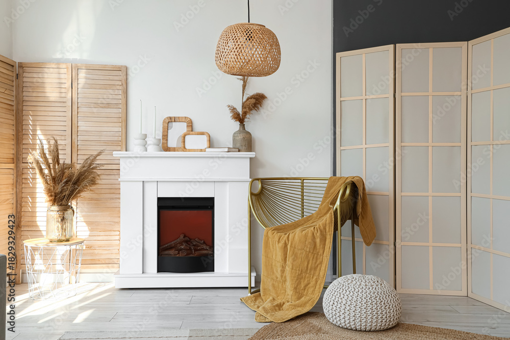 Fototapeta premium Interior of light living room with armchair, fireplace and folding screen
