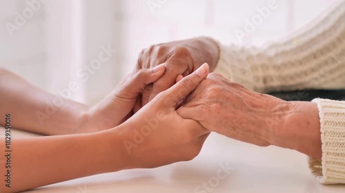 Holding Hands together for Helping and Giving Support. A senior mother sit on sofa while her daughter cover and hold her hands for care and support.