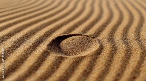 A close-up view of a sandy beach with a large, circular indentation in the center.