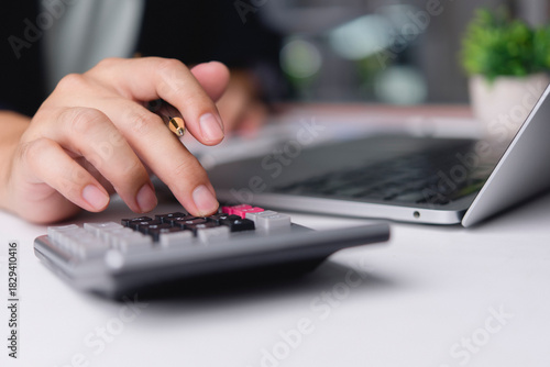 Foto Accountant hand using calculator holding pen computing financial tax office desk laptop