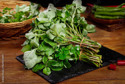 Fresh Watercress Bunch on Black Slate with Rustic Wooden Background