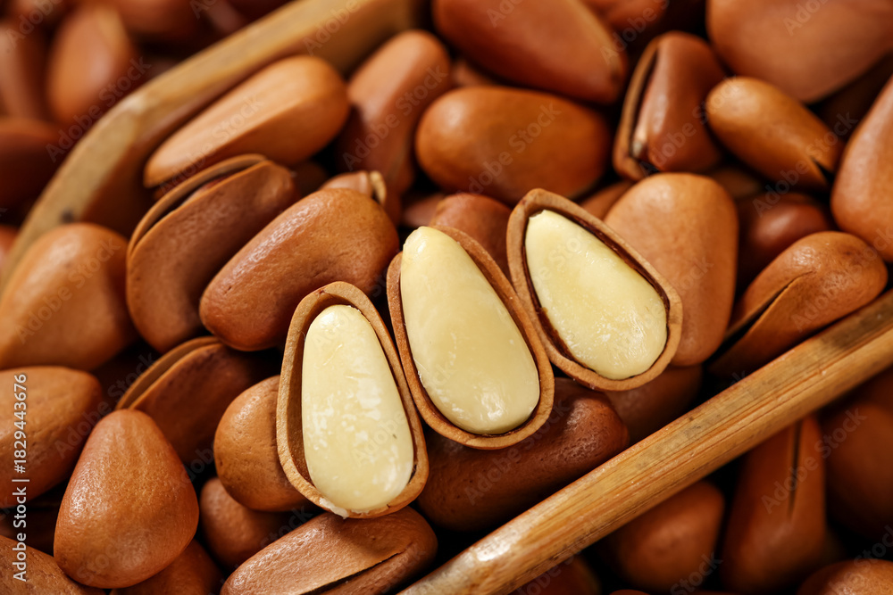 Obraz premium Hand-peeled pine nuts with open shells revealing white kernels, natural healthy food ingredient