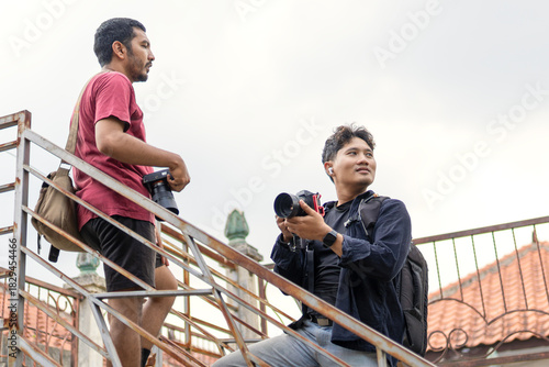 Two photographers walking and reviewing shots in a narrow alley