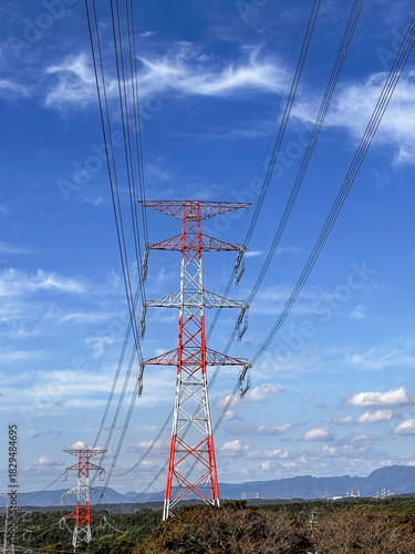 青空の下に立つ赤白の送電線鉄塔と高圧線の風景｜送電線,鉄塔,青空,インフラ