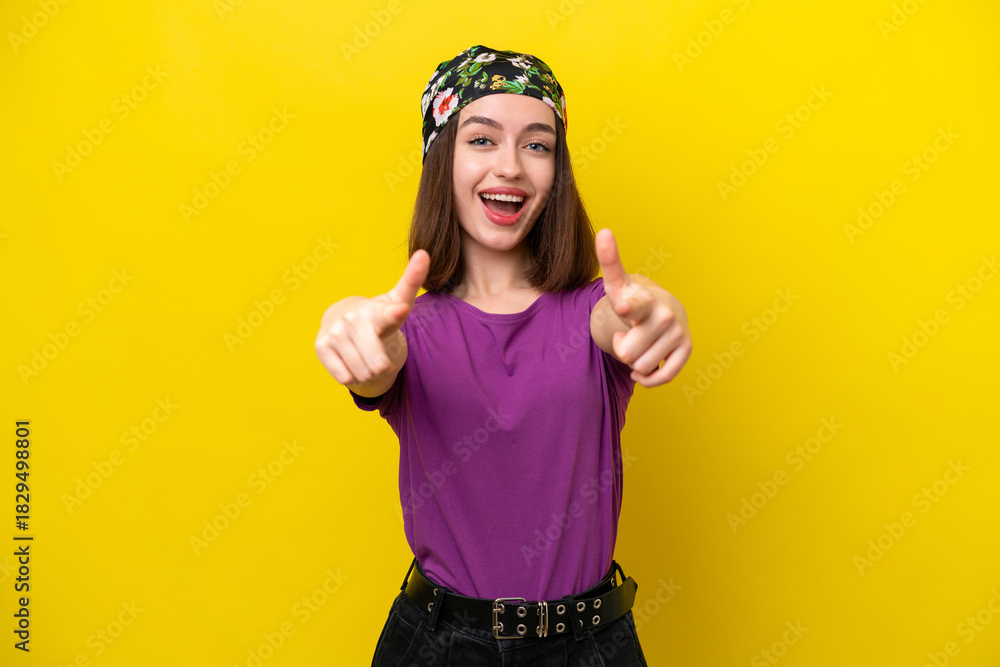 Fototapeta premium Young Ukrainian woman isolated on yellow background surprised and pointing front