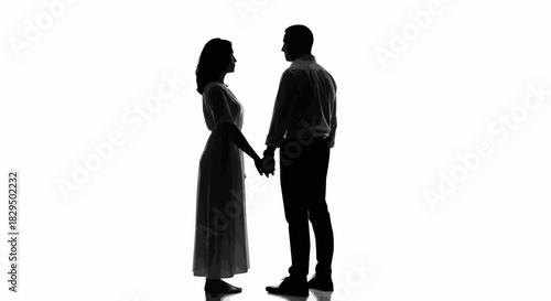Silhouette of a couple holding hands facing each other.
