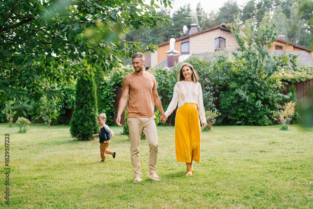 Obraz premium Pregnant Mother And Father Walking With Child In Garden
