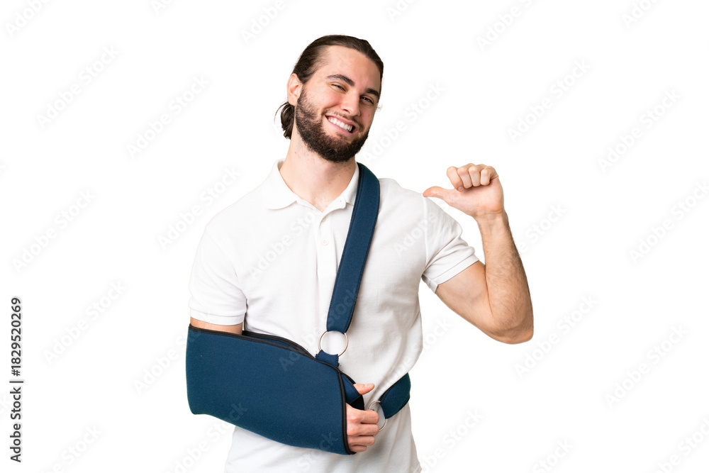 Fototapeta premium Young handsome man with broken arm and wearing a sling over isolated chroma key background proud and self-satisfied